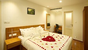 Una habitació d'hotel amb un llit ben fet, una taula de treball amb una cadira, un mirall i una porta.