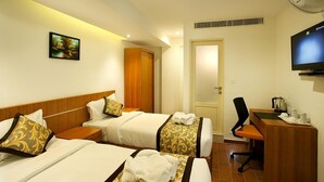 Habitació d'hotel amb dos llits, un escriptori, una cadira, una televisió i un quadre a la paret.