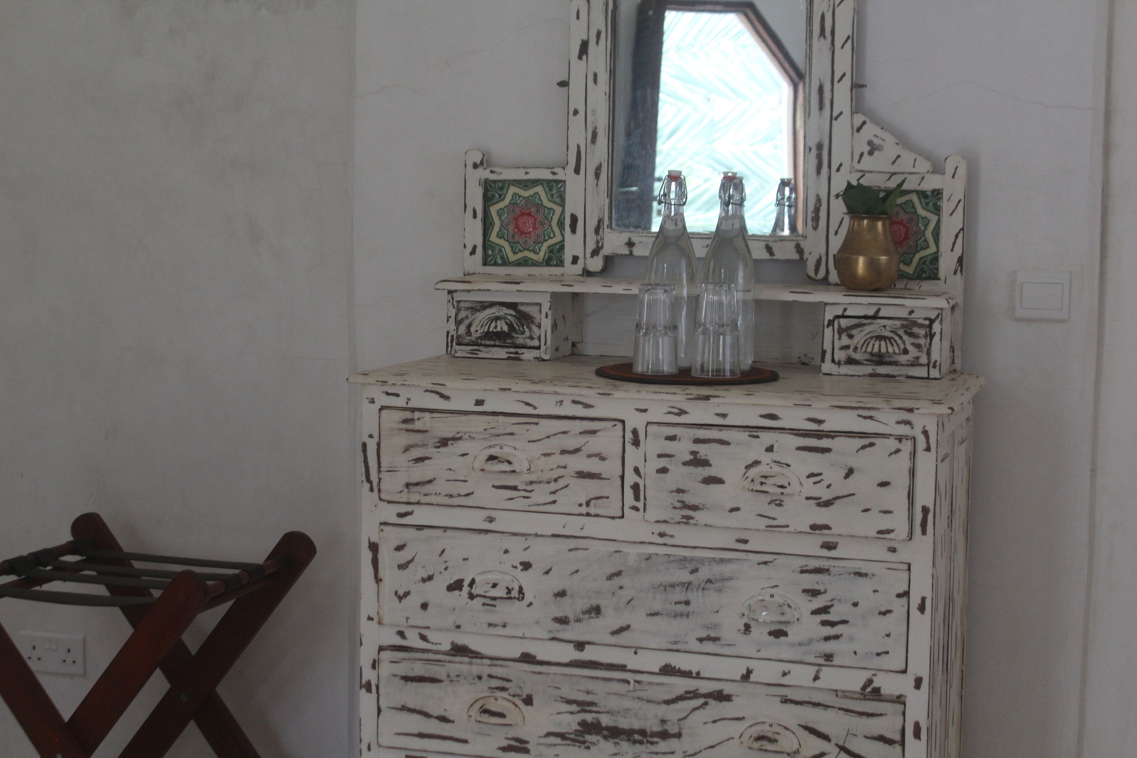A white dresser with decorative panels and a mirror above it.