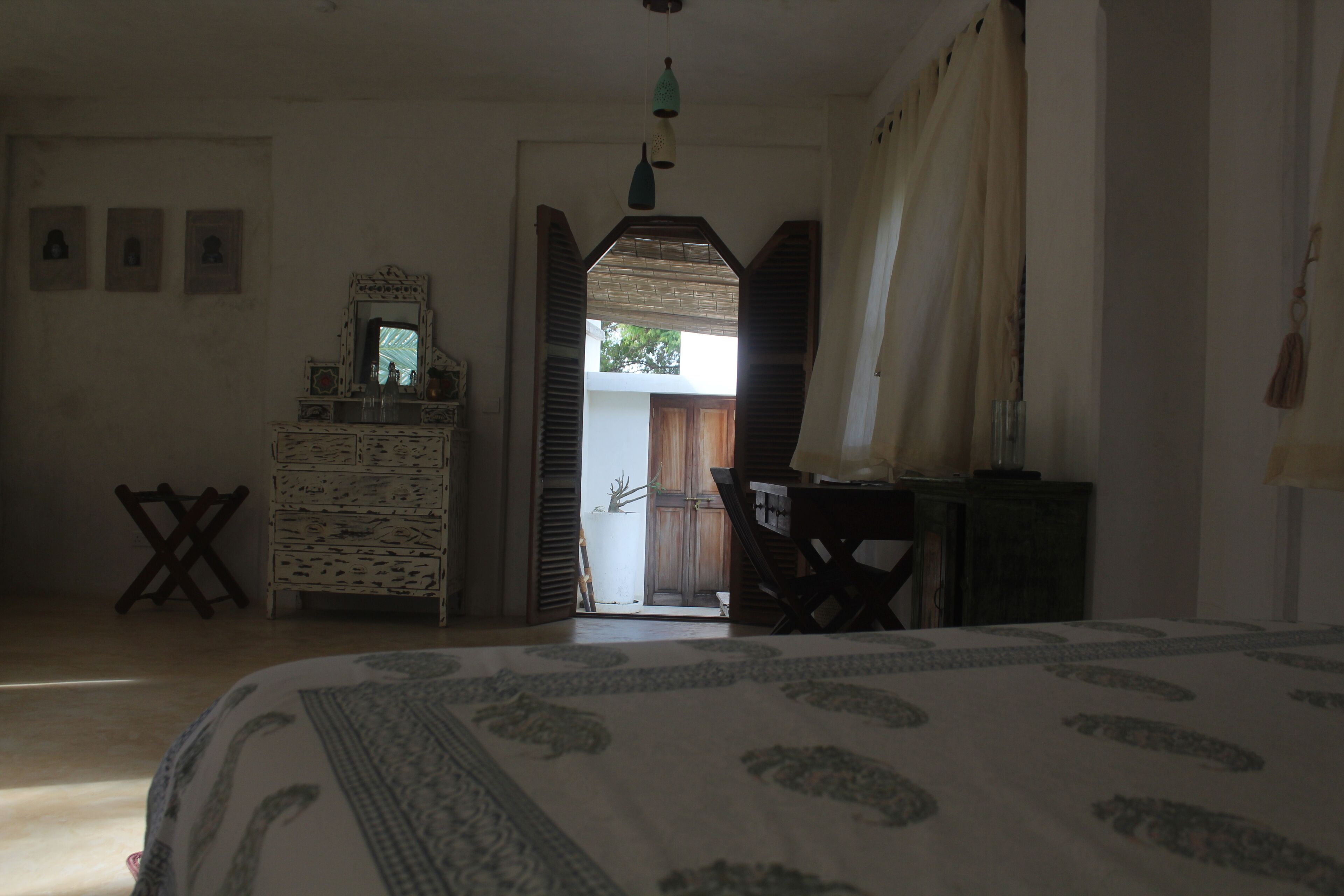 A bedroom with a bed, dresser, and a view of the outside.