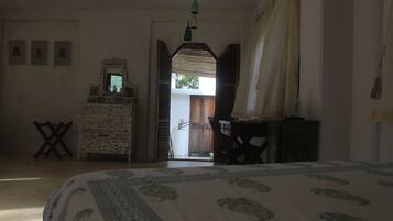 A bedroom with a bed, dresser, and a view of the outside.
