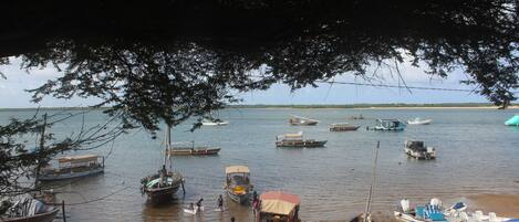 A beach with several boats docked and people walking along the shore.