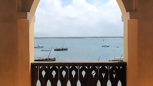 A view through an arched window of a body of water with several boats. - Kijani Hotel (Lamu)