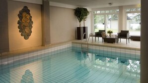 A swimming pool with tiled flooring, a wall-mounted sculpture, and a potted plant.