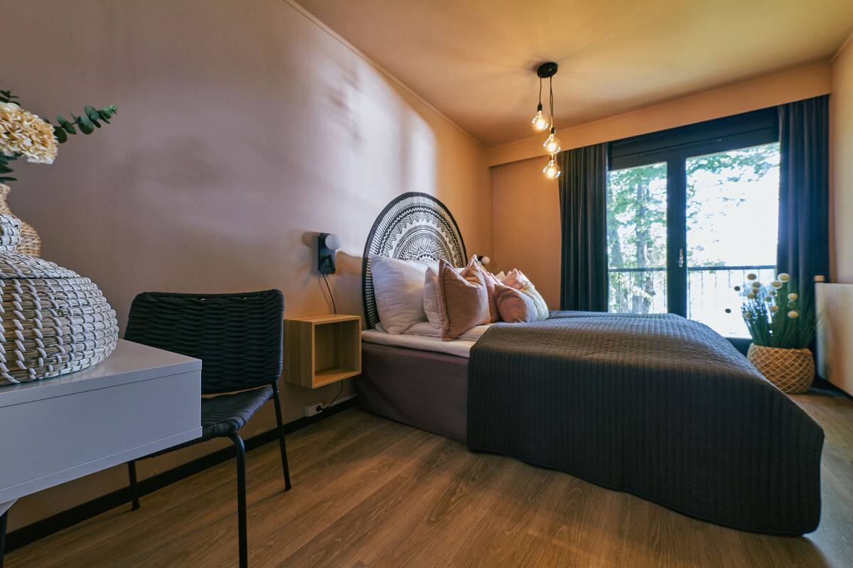 Una camera da letto moderna con un letto, un comodino, una sedia e vista sull'esterno.