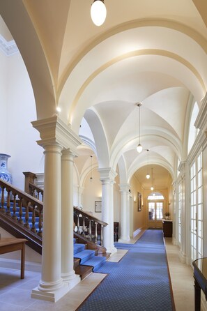 A grand hallway with high ceilings, large columns, and a wooden staircase. - Blervie House (Forres)