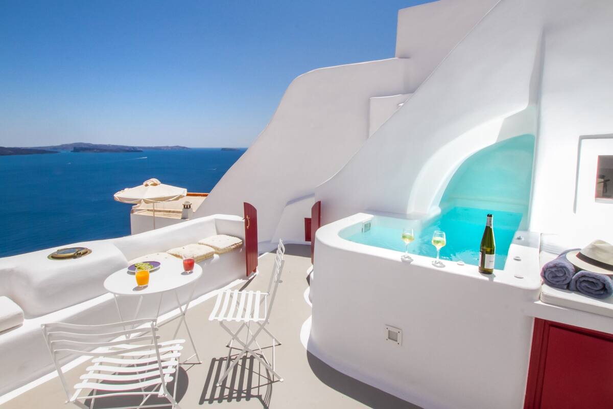 Un yacht blanc équipé d’un jacuzzi, de deux chaises, d’une table avec des boissons et d’une bouteille de vin.