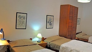 A hotel room with two single beds, a wooden wardrobe, and two bedside lamps. - Tagus Host (Santarém)