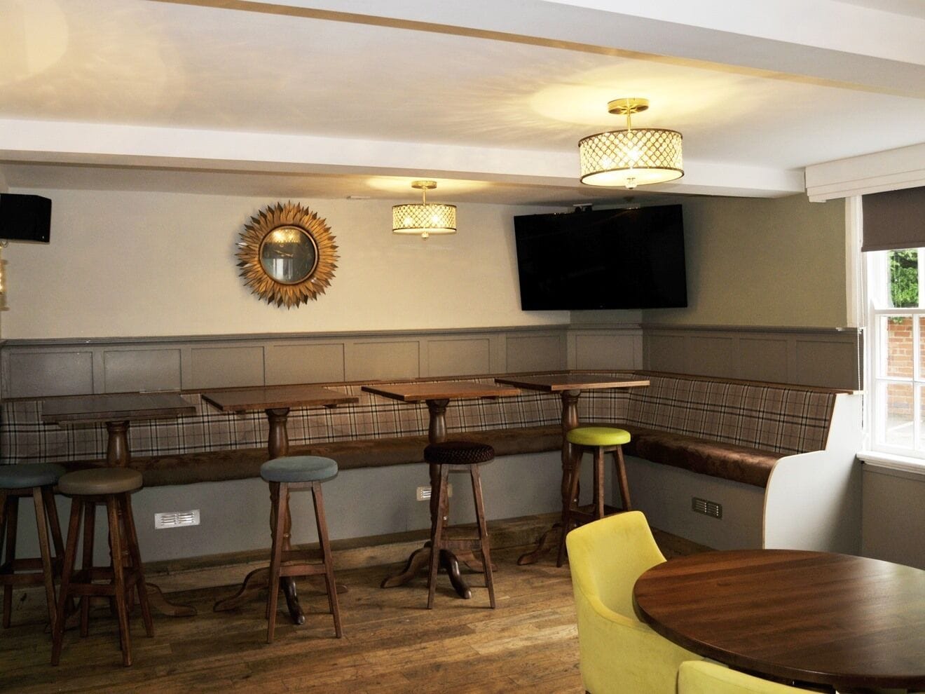 Un espace bar avec des tabourets en bois, un banc et un téléviseur fixé au mur.
