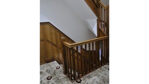 Una escalera de madera con barandilla, peldaños alfombrados y un muro de madera.