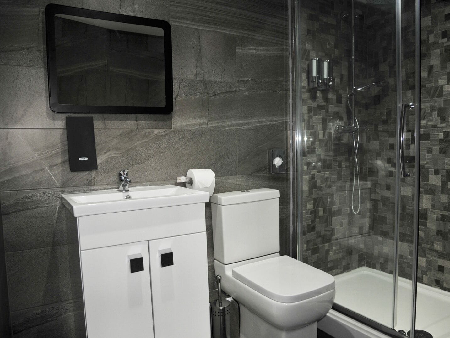 A modern bathroom with a glass-enclosed shower, a white sink, and a toilet.