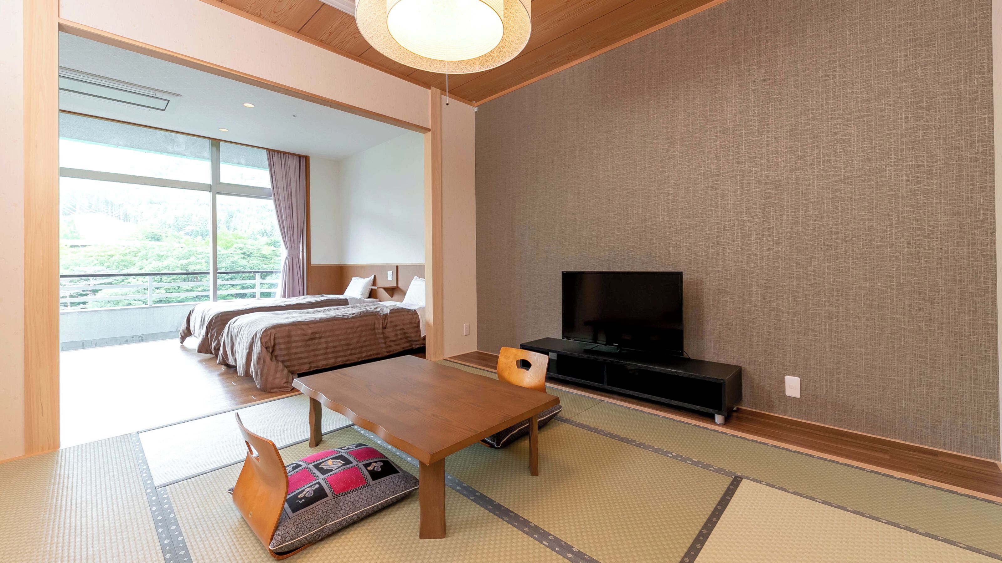 A hotel room with a bed, a TV, a dining table, and tatami mats.
