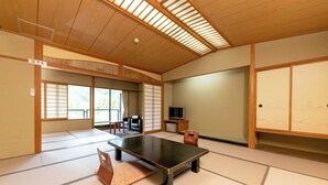Una habitación japonesa tradicional con suelo de tatami, una mesa baja, un televisor y puertas correderas.