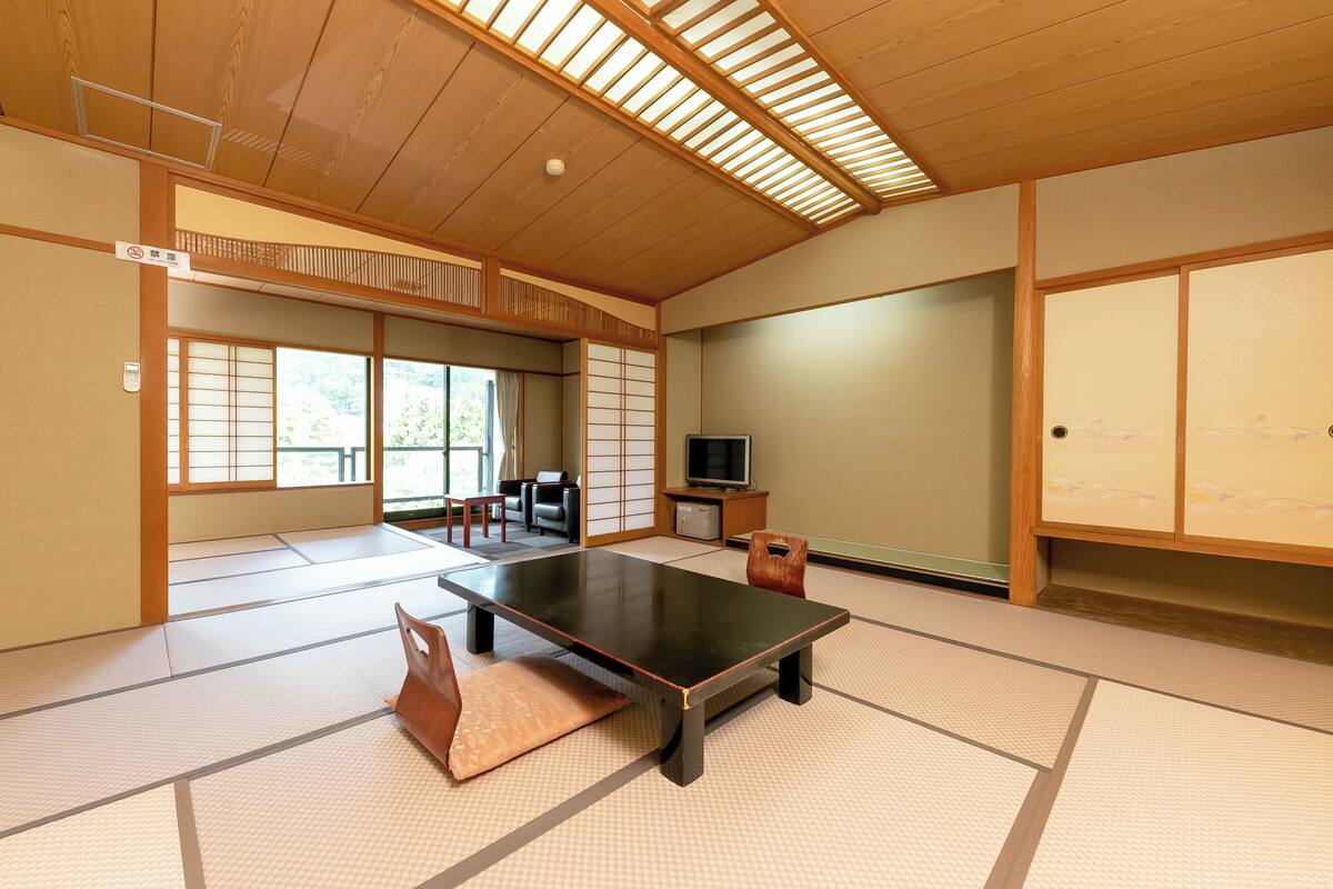 Ett traditionellt japanskt rum med tatamimattor p å golvet, ett lågt bord, en tv och skjutdörrar.