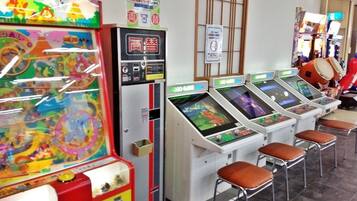 A row of arcade machines with stools in front, a colorful game machine, and a sign on the wall.