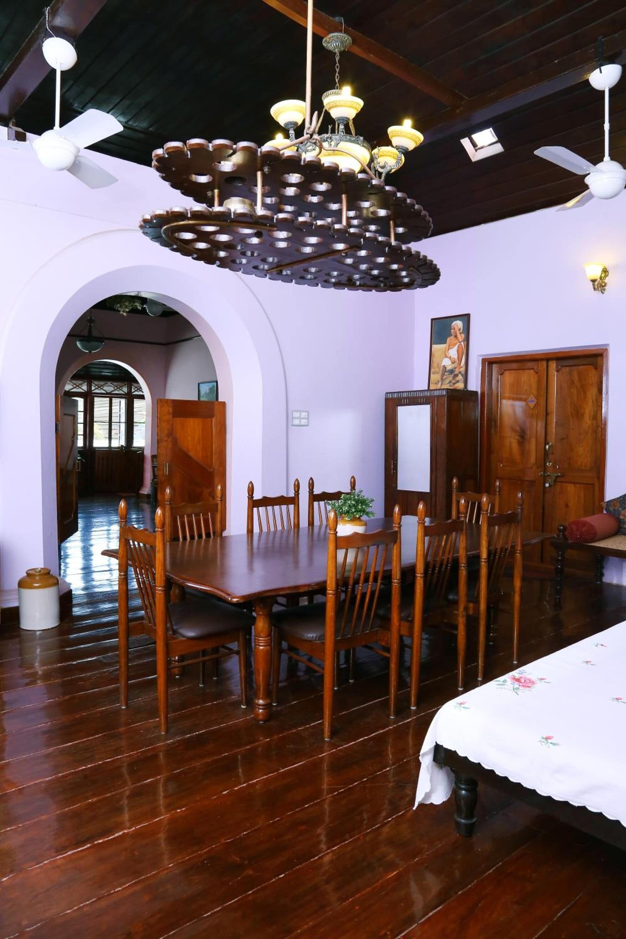 Uma sala de jantar com mesa e cadeiras de madeira, um candelabro e uma porta de madeira.