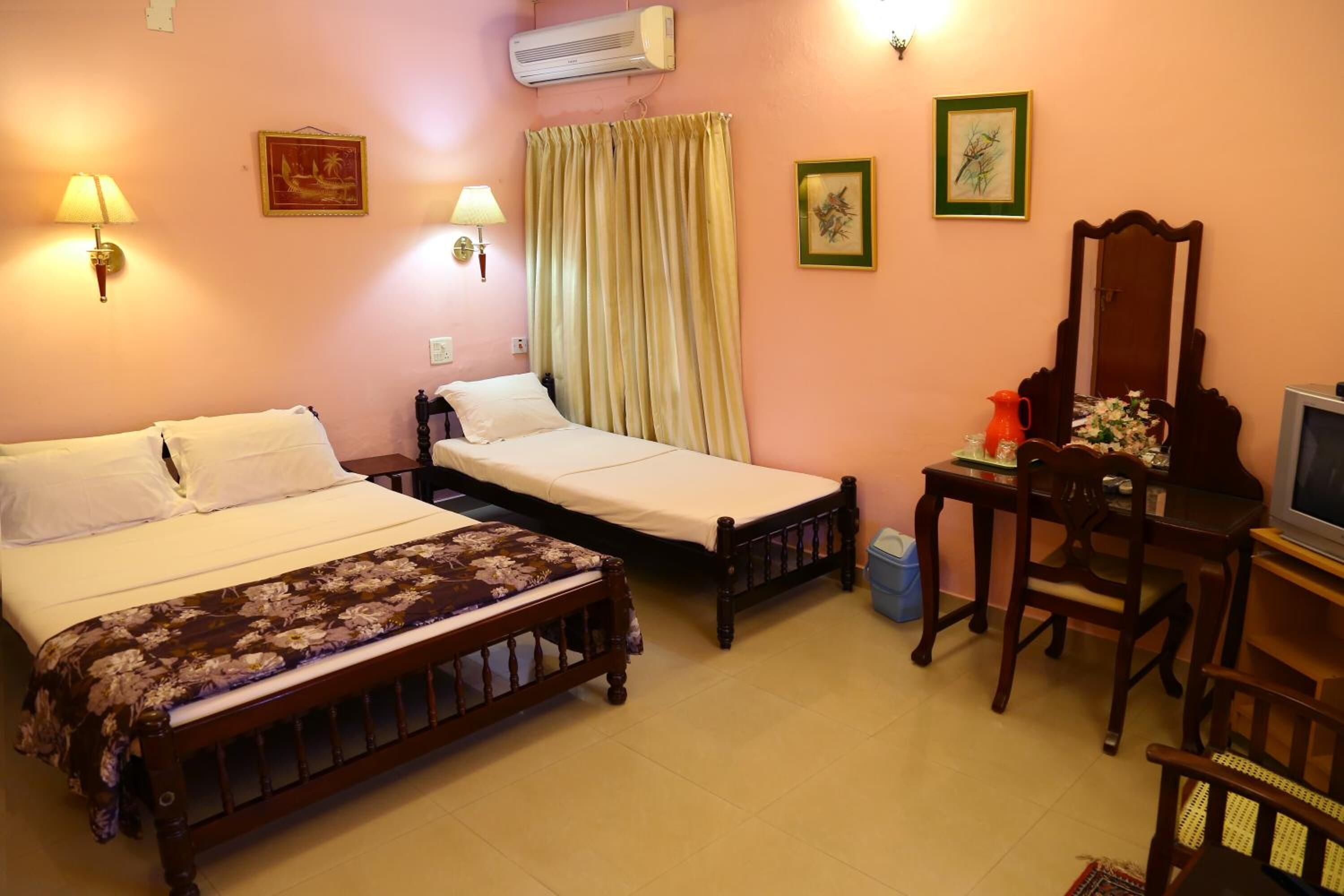 A hotel room with two single beds, a desk with a chair, a television, and a mirror.
