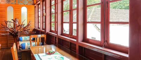A traditional wooden interior with large windows, a wooden bench, and a table with a placemat.