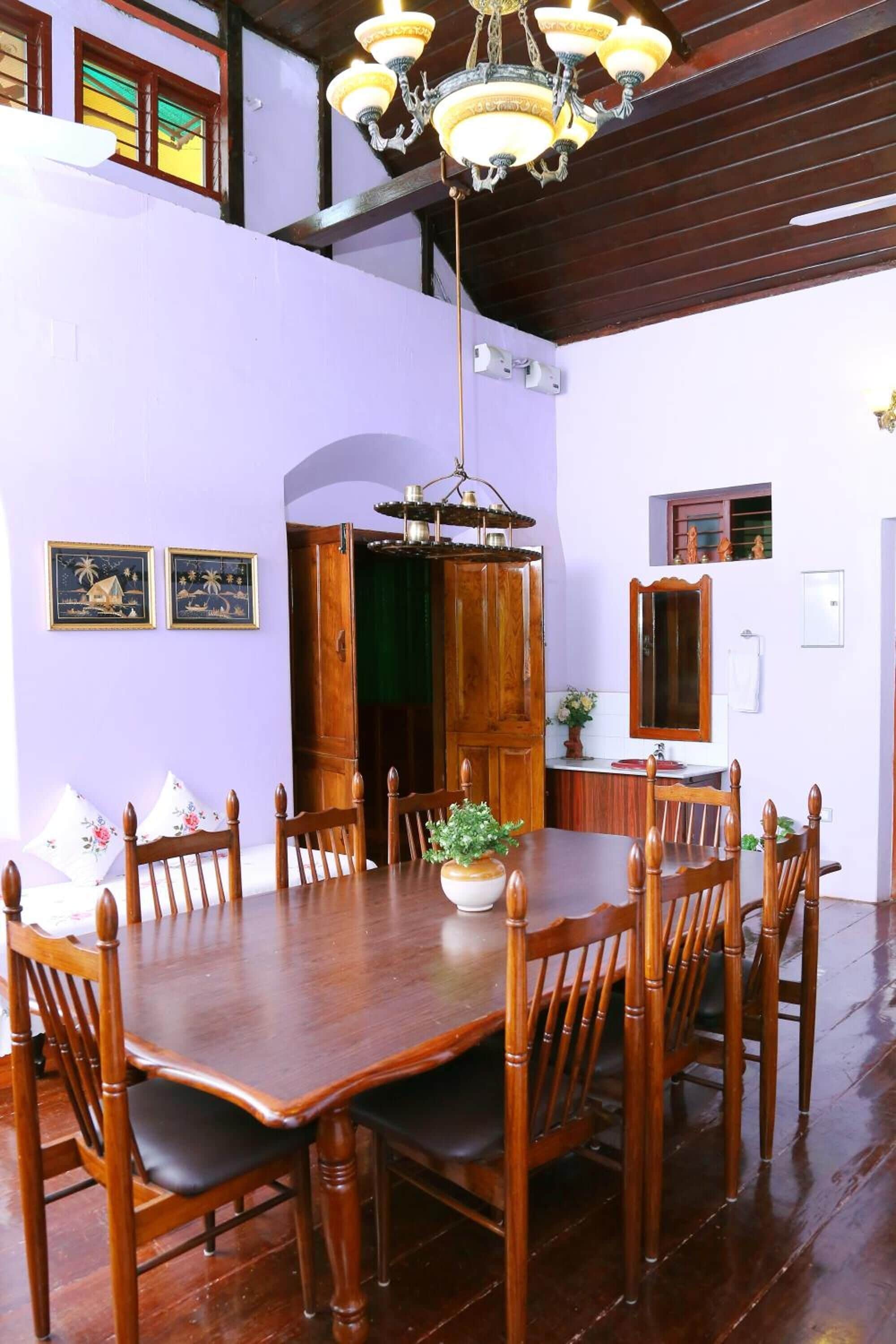 A dining area with a wooden table and chairs, a chandelier, and a green door.