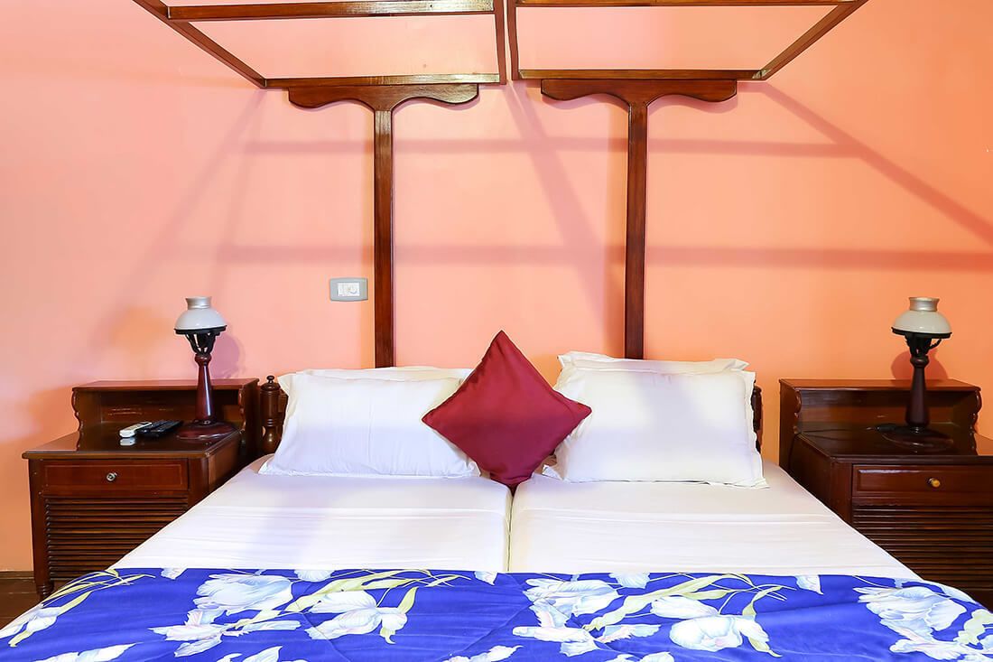 A double bed with a floral bedspread, two nightstands with lamps, and a wooden headboard.