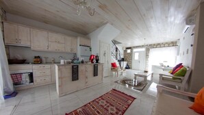 Una cocina amplia con armarios blancos, una isla central y un comedor con una mesa blanca y cojines de colores.