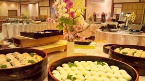 Un buffet proposant divers plats, notamment un grand saladier rempli de raviolis blancs, décorés de feuilles vertes, et un autre saladier contenant un plat différent.