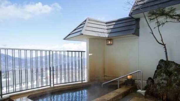 Un espace avec un bain à remous offrant une vue sur les montagnes, doté d’un sol carrelé et d’une rambarde.