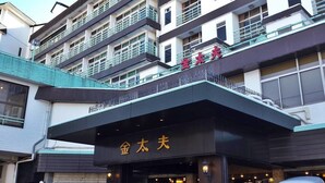 Un immeuble à plusieurs étages, doté de balcons et d’une enseigne sur laquelle on peut lire « 金太夫 ».
