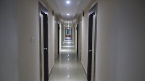 A long, narrow hallway with doors on both sides, leading to a bright room at the end. - Larica Holiday Inn Puri (Puri)