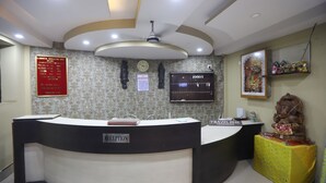 A reception desk with a clock, a TV, and a statue. - Larica Holiday Inn Puri (Puri)