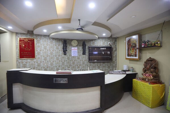 A reception desk with a clock, a TV, and a statue.