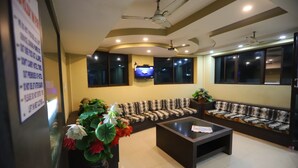 A modern living room with a sofa, a coffee table, and a TV mounted on the wall. - Larica Holiday Inn Puri (Puri)