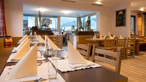 Un restaurante con mesas y sillas de madera, un cartel con el menú y vistas al exterior.
