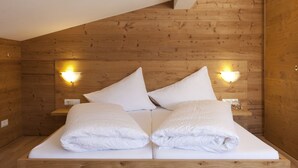 Habitación con paneles de madera, una cama, dos almohadas y dos lámparas fijadas a la pared.