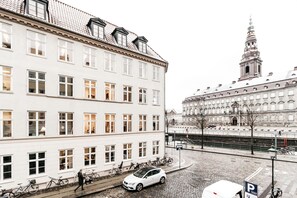 A cobblestone street with a white building featuring multiple windows and a bicycle parked in front.