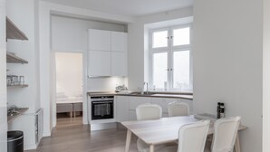 A modern kitchen with white cabinetry, a dining table with chairs, and a window providing natural light.