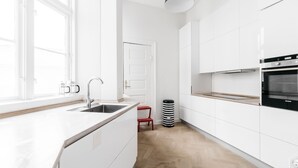 A modern kitchen with white cabinetry, a black oven, and a wooden countertop.