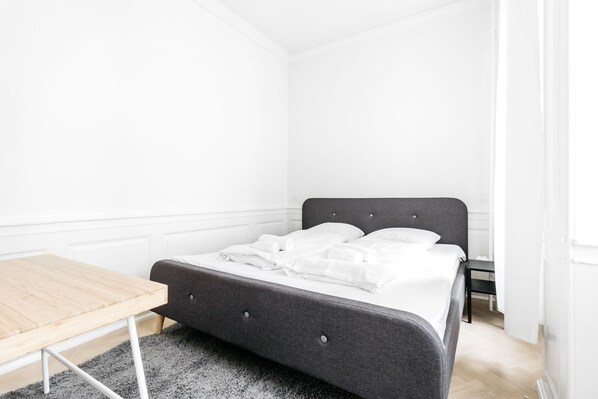 Ein Schlafzimmer mit einem Bett, einem Holztisch und einem kleinen Nachttisch.
