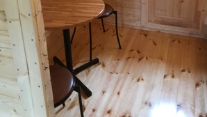 A wooden interior with a round table and two chairs, a door with a hexagonal window, and a curved ceiling. - Framtid Camping Lodging Barrels (Djupivogur)