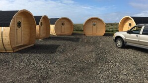 Four wooden bunk beds with a car parked nearby. - Framtid Camping Lodging Barrels (Djupivogur)