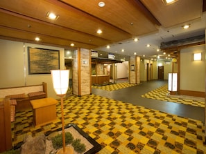 A hotel lobby with a checkered floor, wooden benches, a reception desk, and a traditional Japanese lantern. - Ikaho Grand Hotel (Shibukawa)