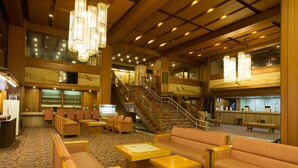 Eine Hotelhalle mit einer zentralen Treppe, Sitzbereichen und einer Rezeption.