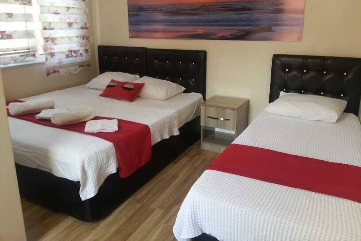 A hotel room with two beds, a nightstand, and a painting of a sunset.