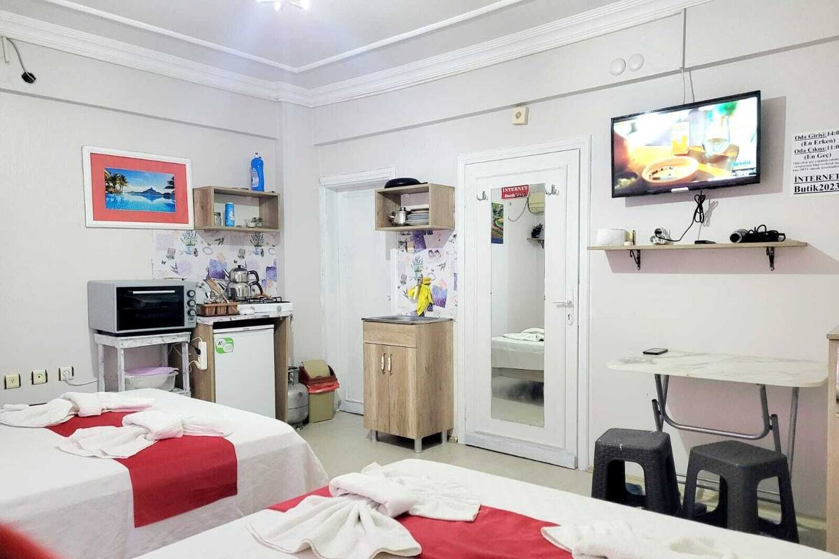 A hotel room with two beds, a kitchenette, a TV, and a bathroom door.