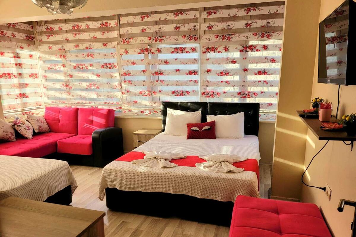 A hotel room with a bed, a sofa, a small table, and a TV.