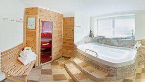 A spa room with a wooden sauna, a stone-tiled floor, a wooden bench with towels, and a large stone-tub. - Appartements OLYMPIA (Schwendau)