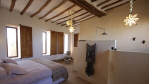 A bedroom with a bed, wooden beams, a hanging light fixture, and a window. - La Parenthese de Marrakech (Tameslouht)