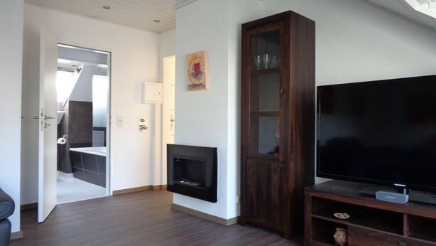 Ein Wohnzimmer mit Flachbildfernseher, einer Holzschrank und einem Kamin.