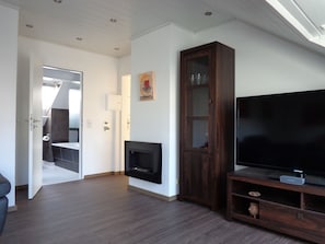 Uma sala de estar com televisão de tela plana, um armário de madeira e uma lareira.