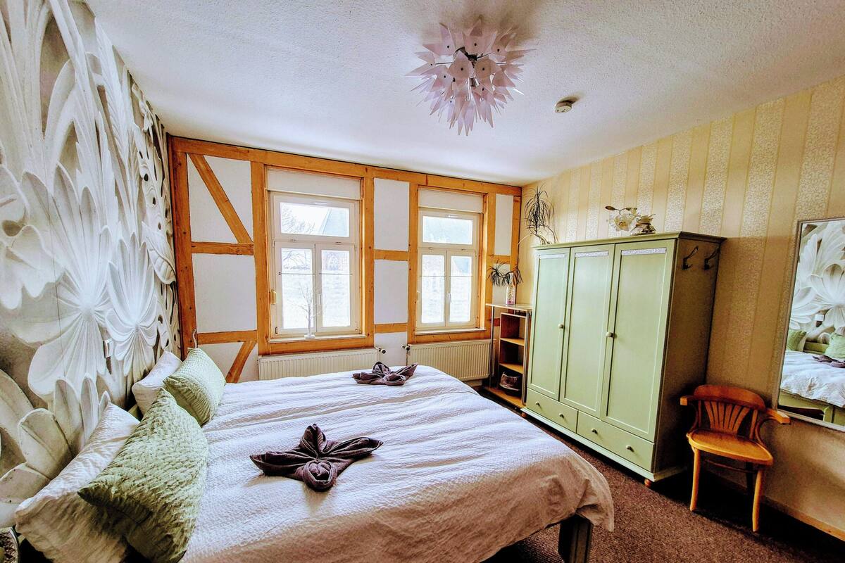 A bedroom with a bed, a wardrobe, a chair, and a window.